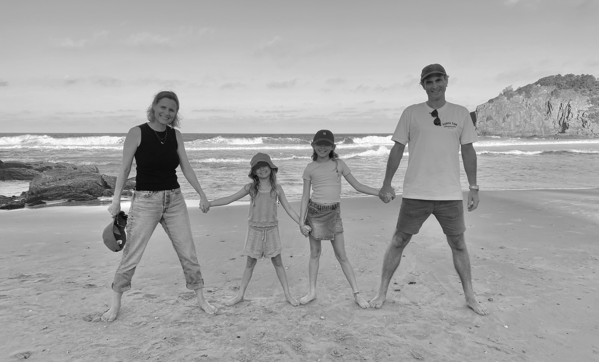 Matt with his family on the beach at the water’s edge, the four of them holding hands in a line